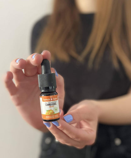 Woman holding a bottle of Formula Swiss CBD oil in MCT oil with orange aroma