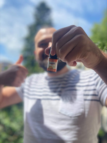 Man outdoors holding up a bottle of Formula Swiss CBD oil in MCT oil with orange aroma