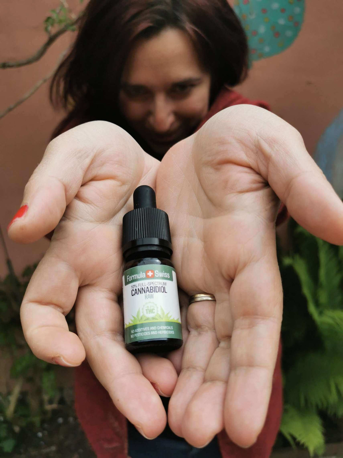 Woman holding a bottle of Formula Swiss RAW CBD oil in hemp seed oil in her open hands