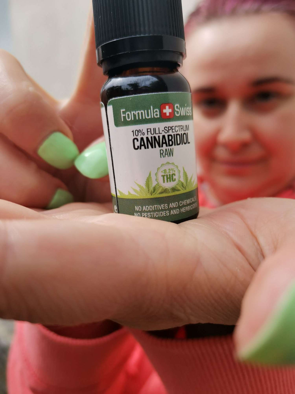 Hand holding a 10% full-spectrum bottle of Formula Swiss RAW CBD oil in hemp seed oil