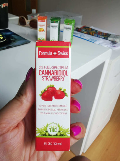 Hand holding the box of Formula Swiss 3% full-spectrum CBD oil in MCT oil with strawberry aroma